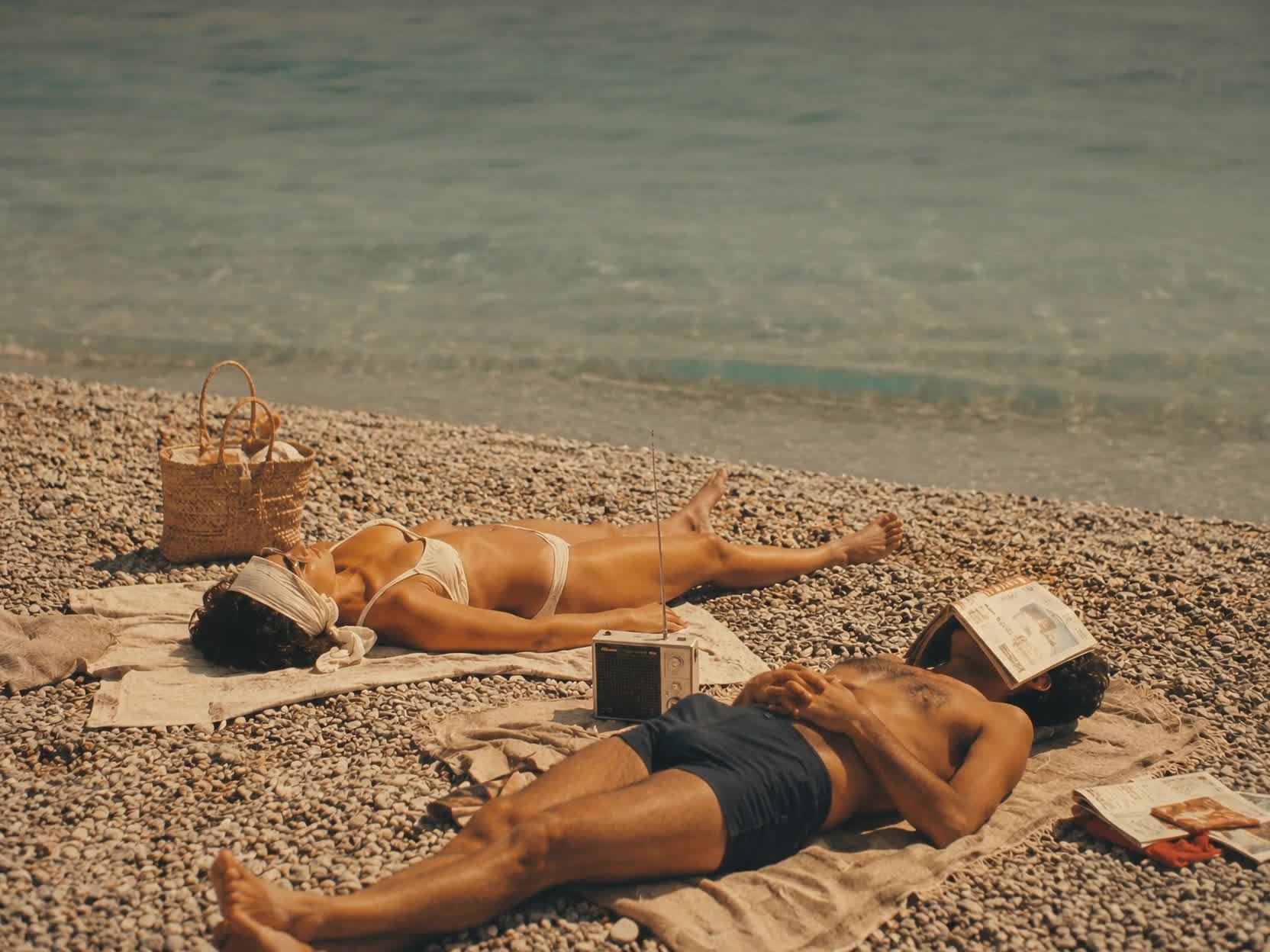 Couple relaxing on a pebble beach beside a vintage radio